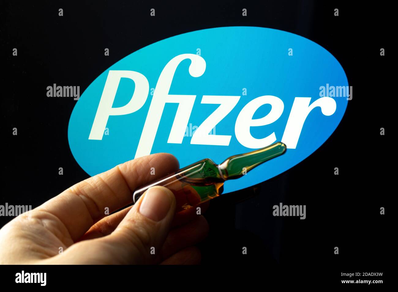 Société pharmaceutique Pfizer de vaccins contre le coronavirus. Logo Pfizer avec vaccin à main. Banque D'Images