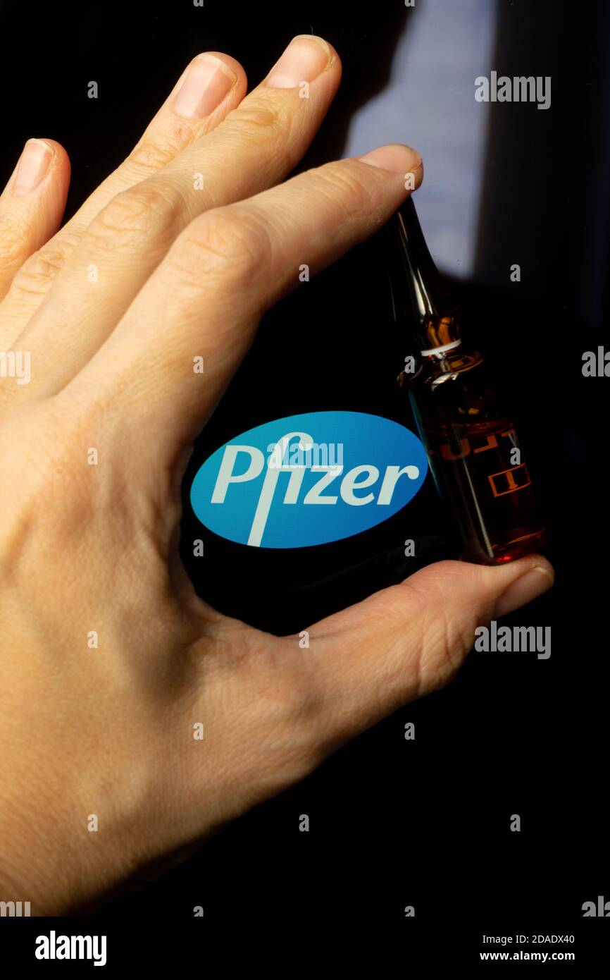 Société pharmaceutique Pfizer de vaccins contre le coronavirus. Logo Pfizer avec vaccin à main. Banque D'Images