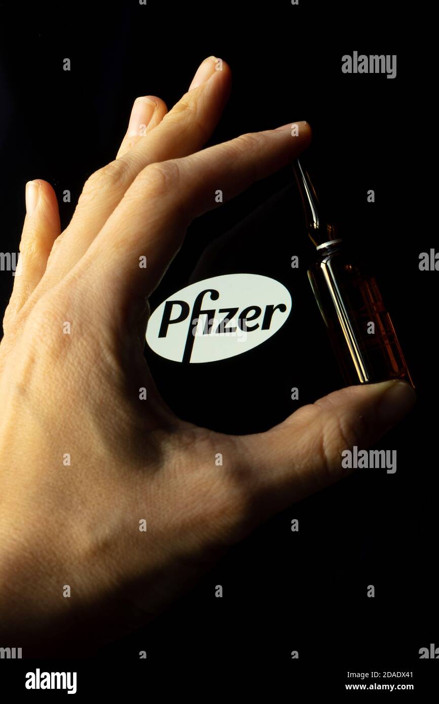 Société pharmaceutique Pfizer de vaccins contre le coronavirus. Logo Pfizer avec vaccin à main. Banque D'Images