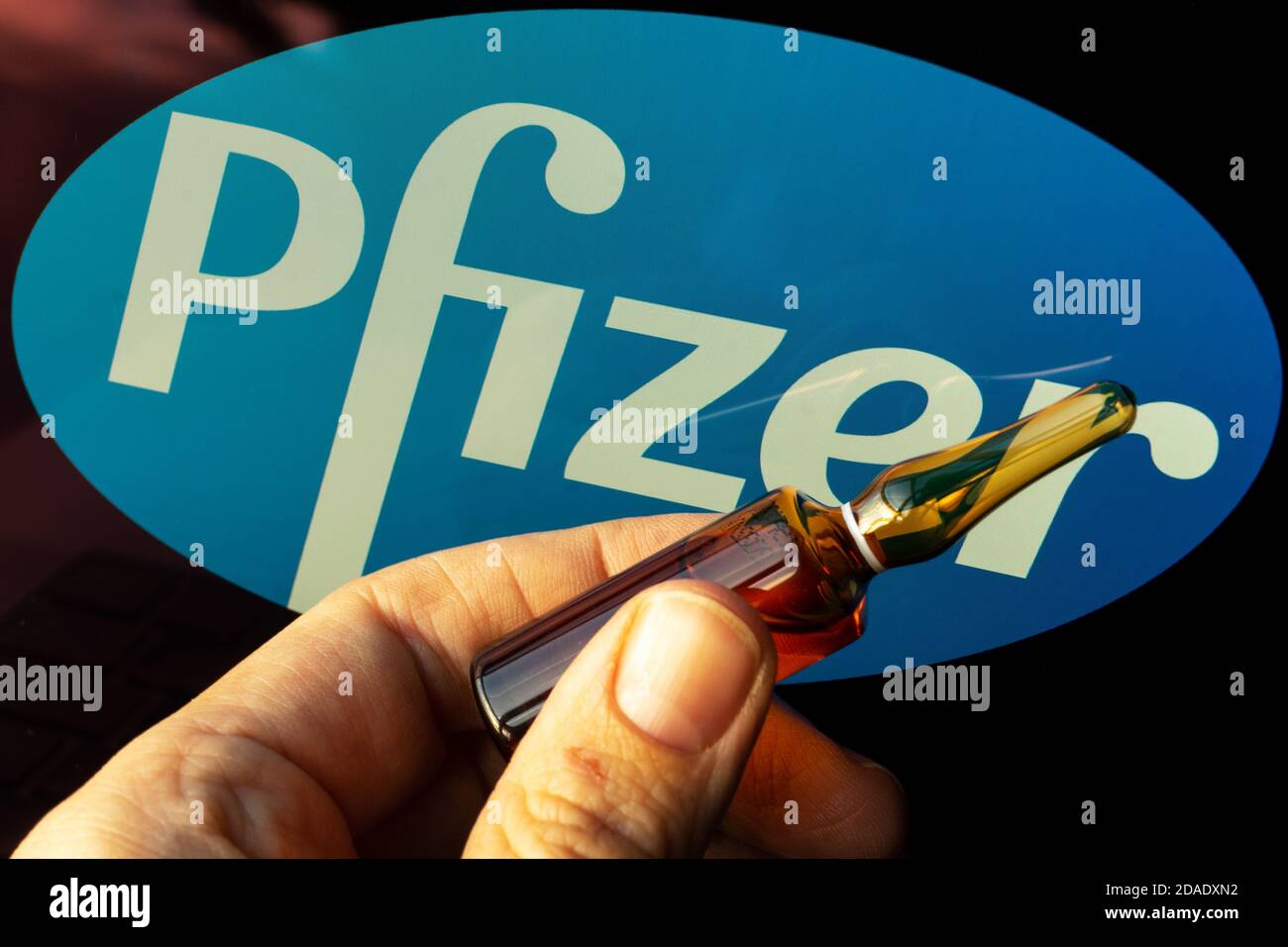 Société pharmaceutique Pfizer de vaccins contre le coronavirus. Logo Pfizer avec vaccin à main. Banque D'Images