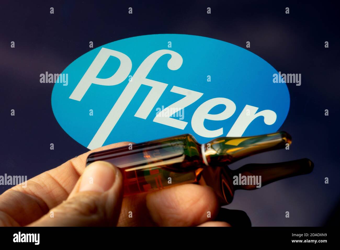 Société pharmaceutique Pfizer de vaccins contre le coronavirus. Logo Pfizer avec vaccin à main. Banque D'Images