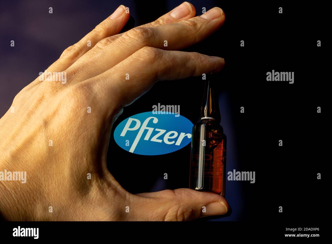 Société pharmaceutique Pfizer de vaccins contre le coronavirus. Logo Pfizer avec vaccin à main. Banque D'Images