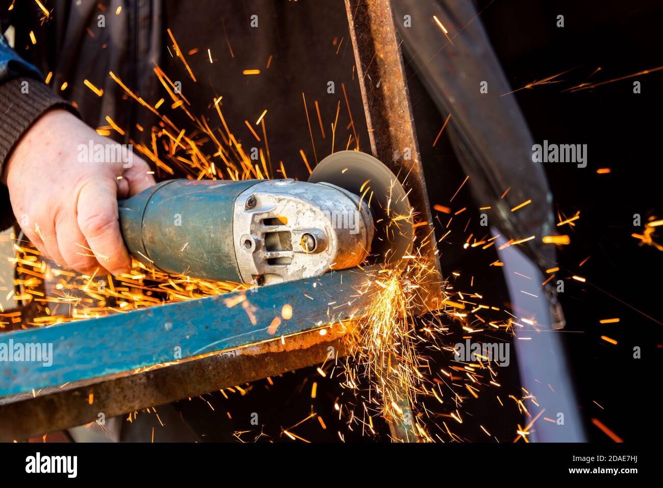 Gros plan sur la scie électrique et les mains de l'homme avec les étincelles. Homme coupant du métal avec une meuleuse, Sparks de la meule Banque D'Images