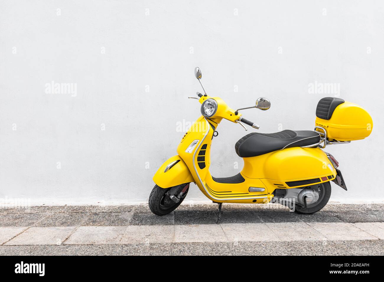 Scooter jaune dans une allée avec mur blanc, moto rétro, croisière en ville Banque D'Images