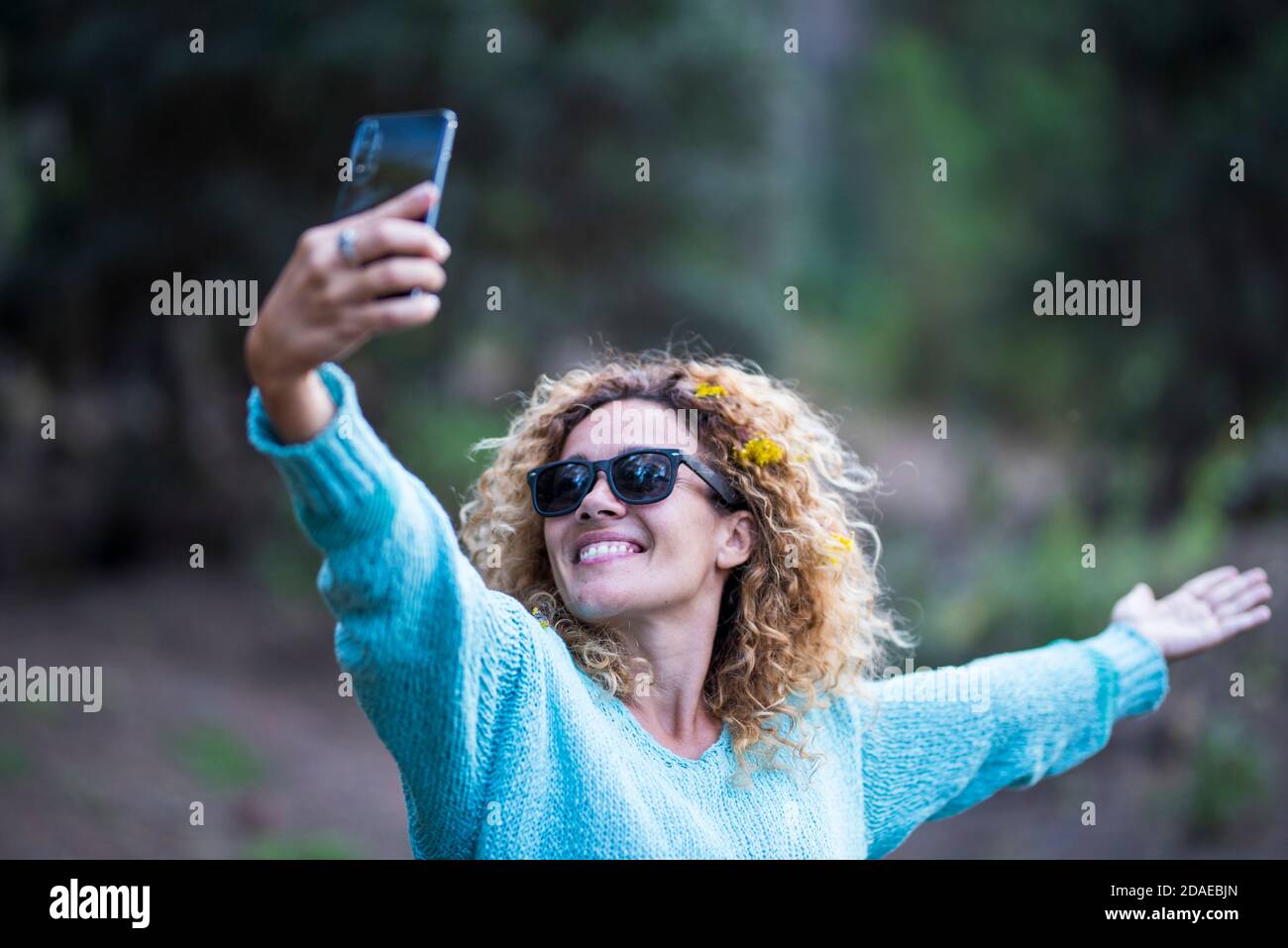 Bonne femme de race blanche adulte qui profite du téléphone pour prendre des photos pour partager sur les médias sociaux - activités de loisirs en plein air et forêt verte en arrière-plan Banque D'Images