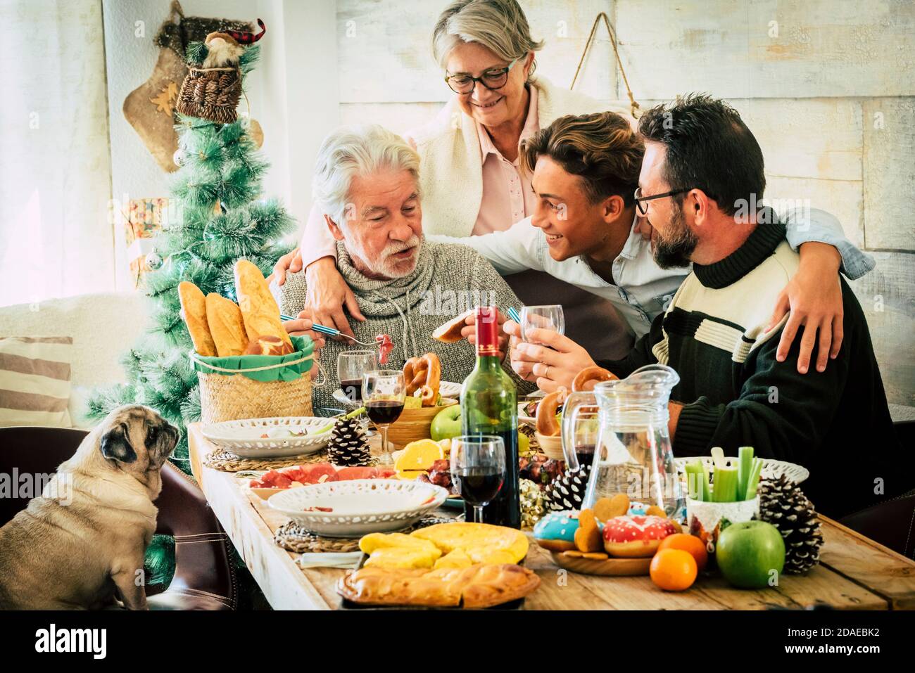 Famille caucasienne joyeuse appréciez et célébrez ensemble à la maison avec table pleine de décorations de noël - âges et générations mixtes de l'adolescent à l'aîné et adulte s'amuser Banque D'Images