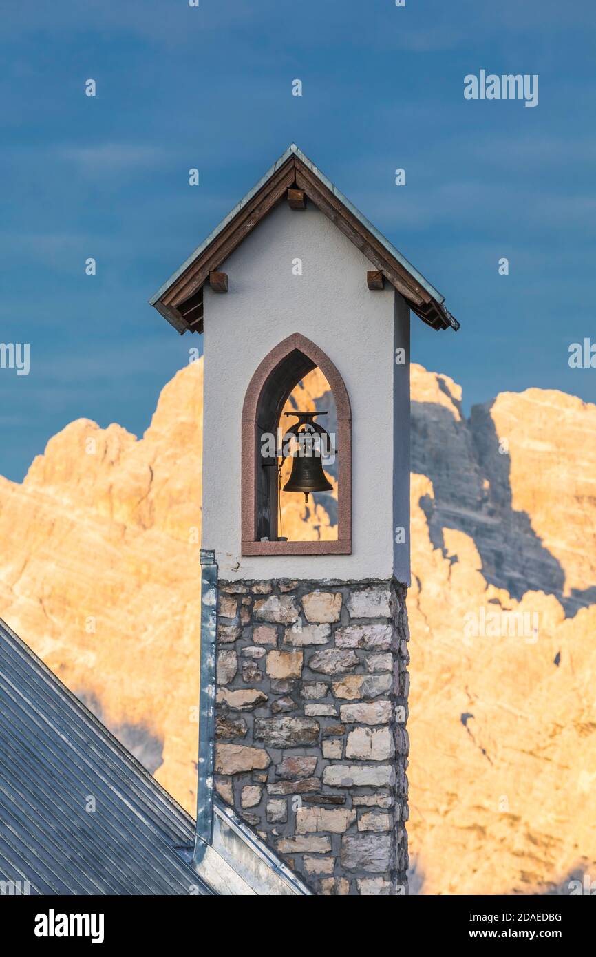 Chapelle de l'Alpini (Cappella degli Alpini) clocher, au pied de la Tre Cime di Lavaredo, en arrière-plan le mont Cristallo embrassé par le soleil, les Dolomites, Auronzo di Cadore, province de Belluno, Vénétie, Italie, Europe Banque D'Images