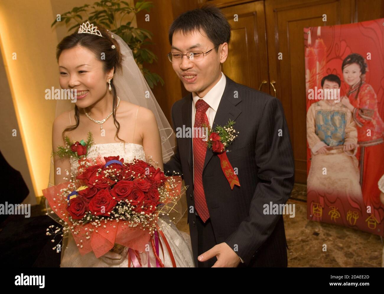 PÉKIN, CHINE - JUIN 2006 : mariée Cheng hui tient un bouquet de roses alors qu'elle et son époux Zhao Jun accueillent les invités arrivant à leur cérémonie de mariage dans un hôtel luxueux de Pékin. Banque D'Images