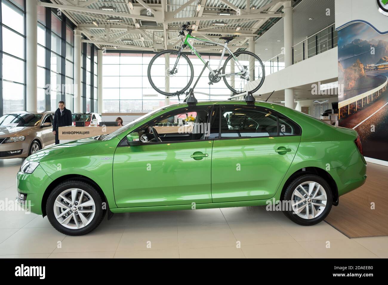 Une voiture verte se tient sous une bicyclette dans la salle d'exposition d'un concessionnaire automobile. Banque D'Images