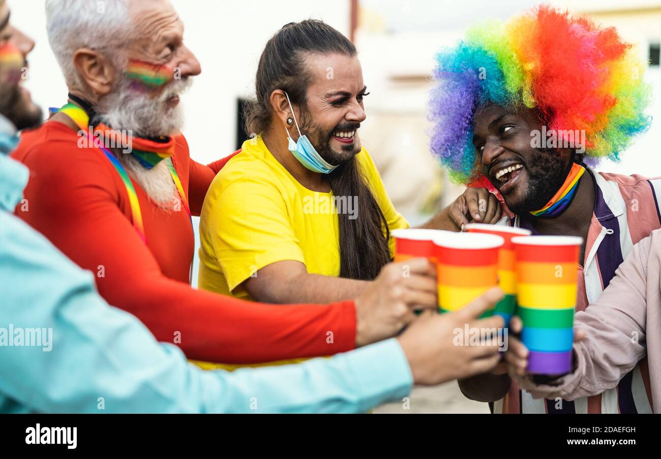 Des gens multiraciaux heureux qui applaudissent et boivent des cocktails dans la fierté gay festival Banque D'Images