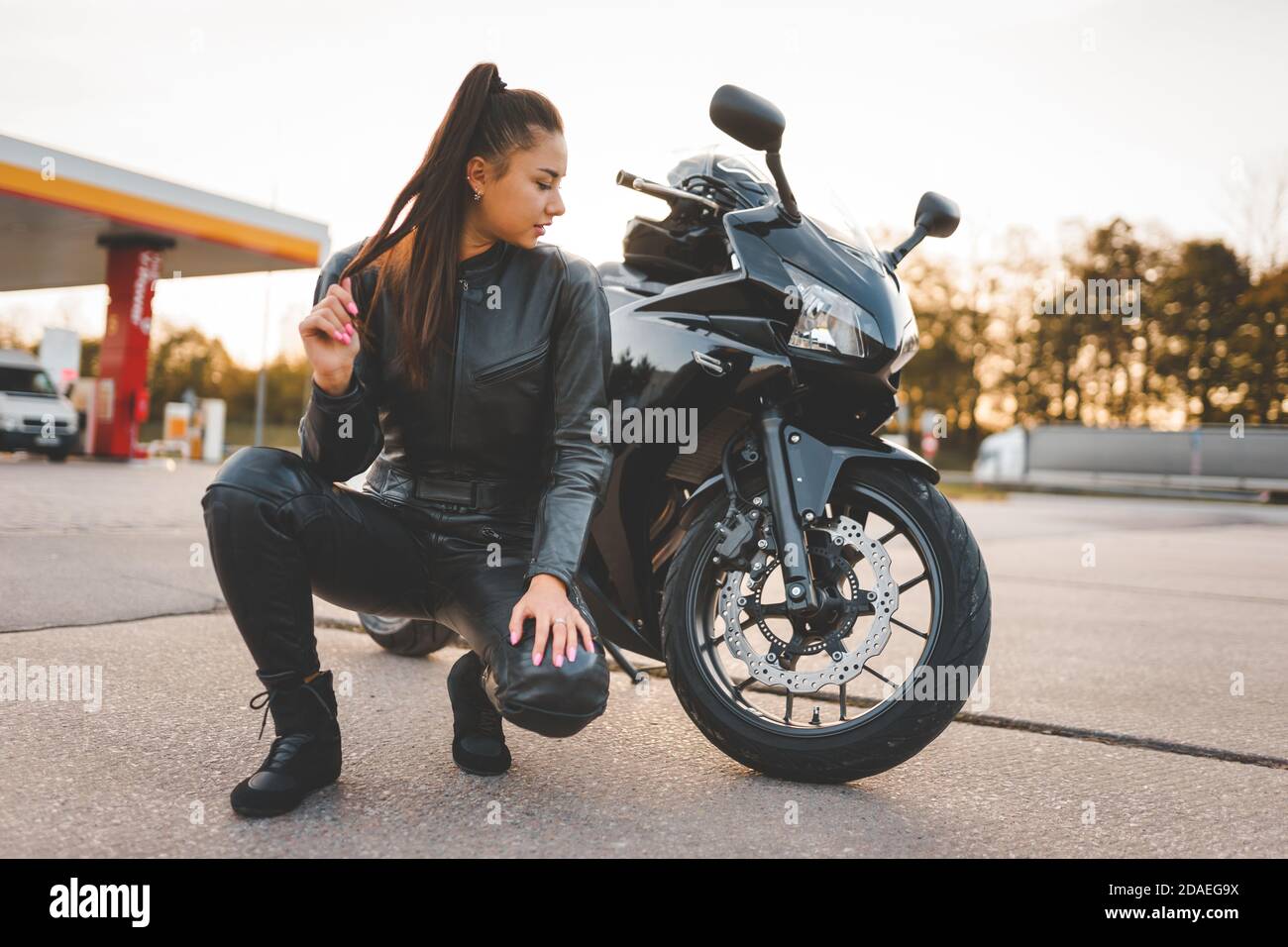 Biker fille dans un costume en cuir près de sa moto Photo Stock - Alamy
