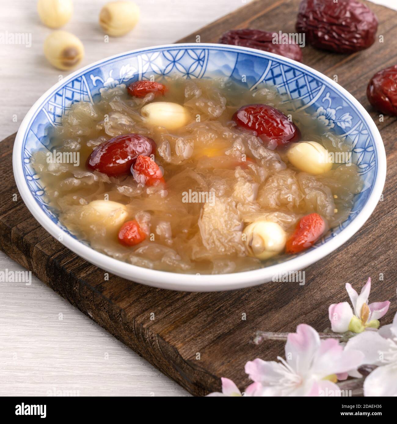 Gros plan de la soupe traditionnelle chinoise douce aux champignons blancs avec graines de lotus, dattes rouges (jujujube) et baies de carcajou (baie de goji, baie de gogyberry) sur le dos blanc Banque D'Images