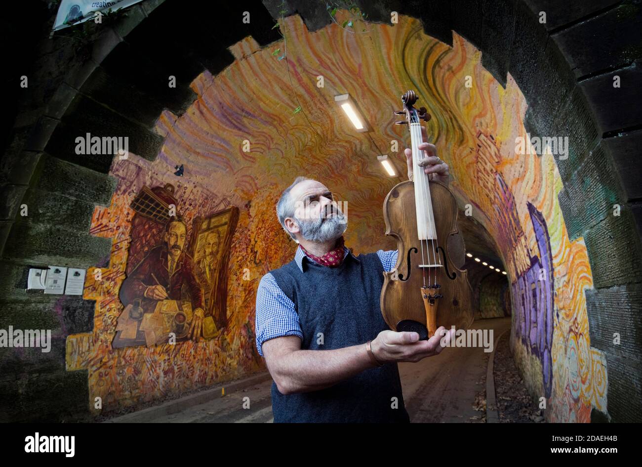 Luthier Steve Burnett, à la fresque du tunnel ferroviaire de Colinton à Édimbourg, tenant un violon unique qu'il a fait pendant son confinement en hommage à Robert Louis Stevenson pour marquer le 170e anniversaire depuis la naissance de l'auteur d'Édimbourg, célèbre dans le monde entier. Banque D'Images