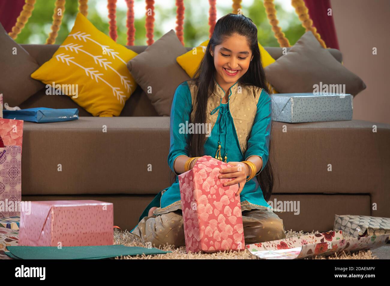 Jeune fille préparant des cadeaux et les emballer tout en étant assis bas Banque D'Images
