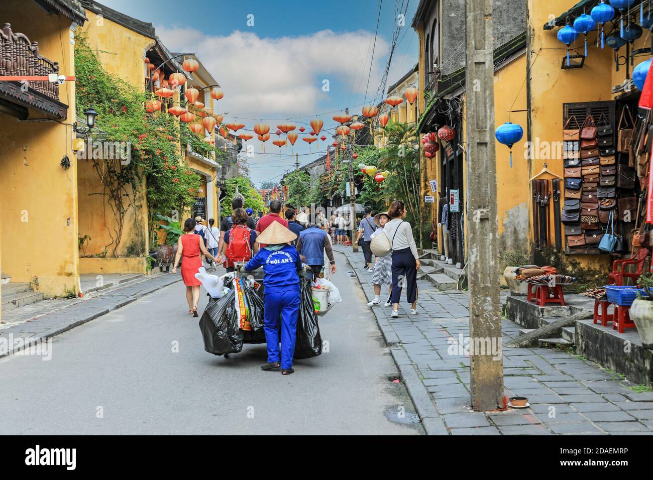 Une femme nettoyant de rue portant un chapeau conique vietnamien traditionnel dans une rue secondaire à Hoi an, Vietnam, Asie Banque D'Images