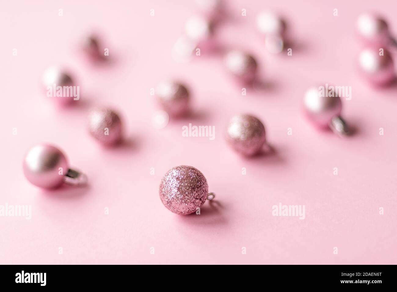 Gros plan sur des décorations de boule de Noël brillantes sur fond rose, mise au point douce. Banque D'Images