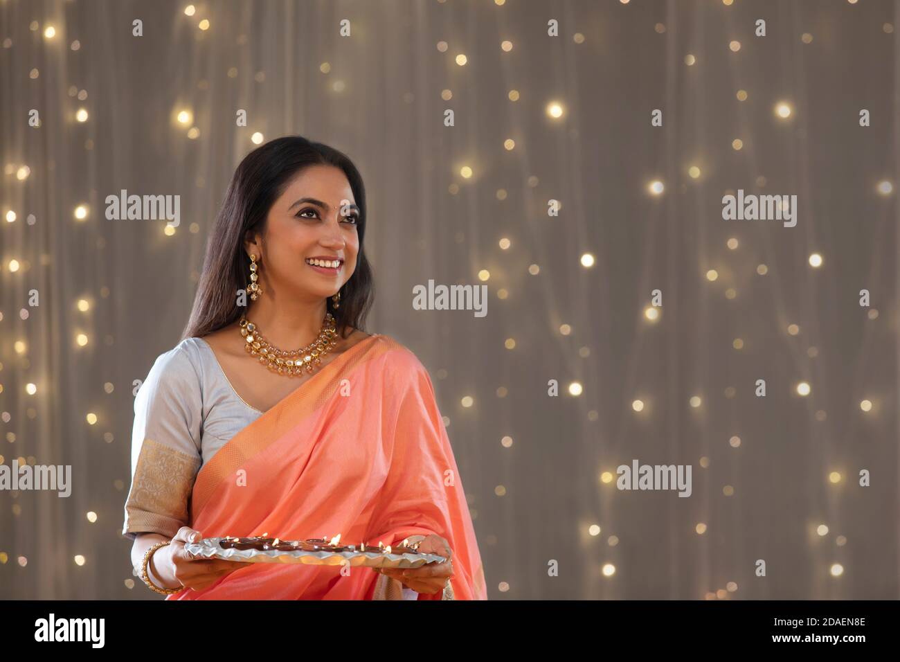 Femme d'âge moyen tenant des diyas et regardant vers le haut Banque D'Images