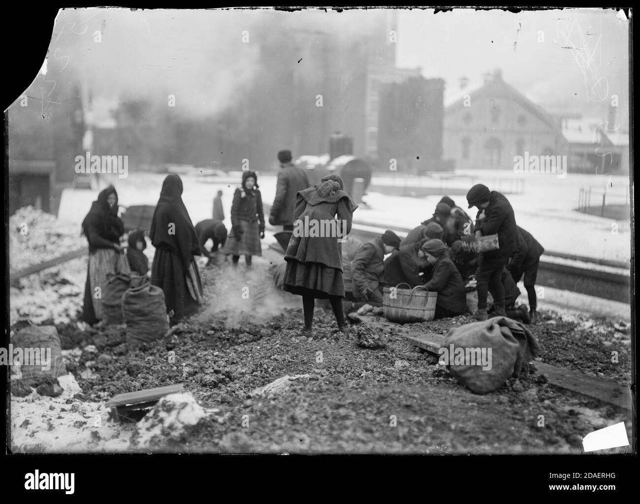 Les femmes et les enfants ramassant le charbon du sol dans les cours de charbon pendant l'hiver à Chicago, Illinois, vers 1902. Banque D'Images