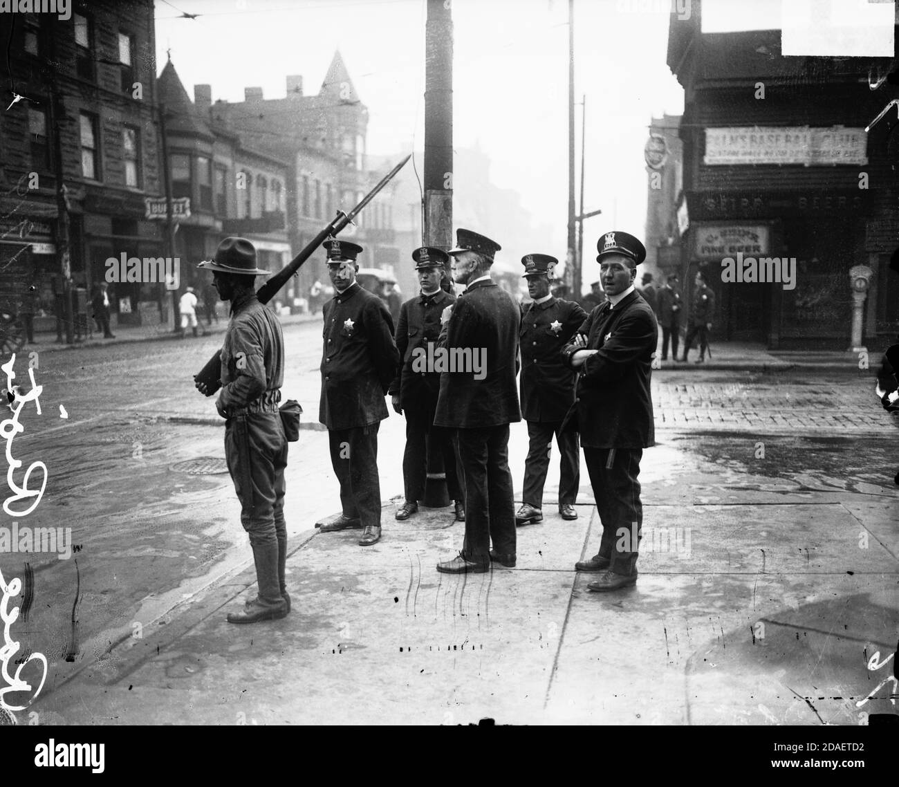 Vue de cinq policiers et d'un soldat avec un fusil, debout au coin de la rue pendant une course à pied, Chicago, Illinois, vers 1919. Banque D'Images