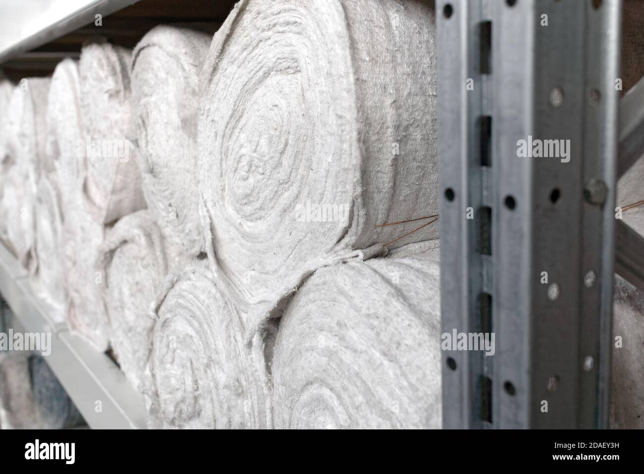 Le matériel blanc en rouleaux se trouve sur les étagères de l'entrepôt. Matériau de couverture. Textiles pour la production de chiffons. Banque D'Images