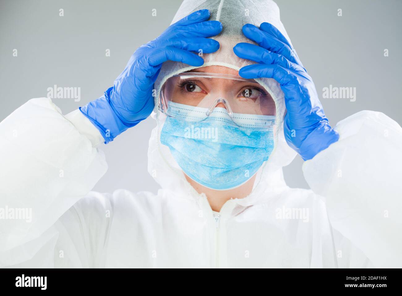 Travailleur médical désespéré NHS EMS en costume blanc de protection, bleu chirurgical Masque gants en latex et lunettes de sécurité, coronavirus COVID-19 crise pandémique Banque D'Images