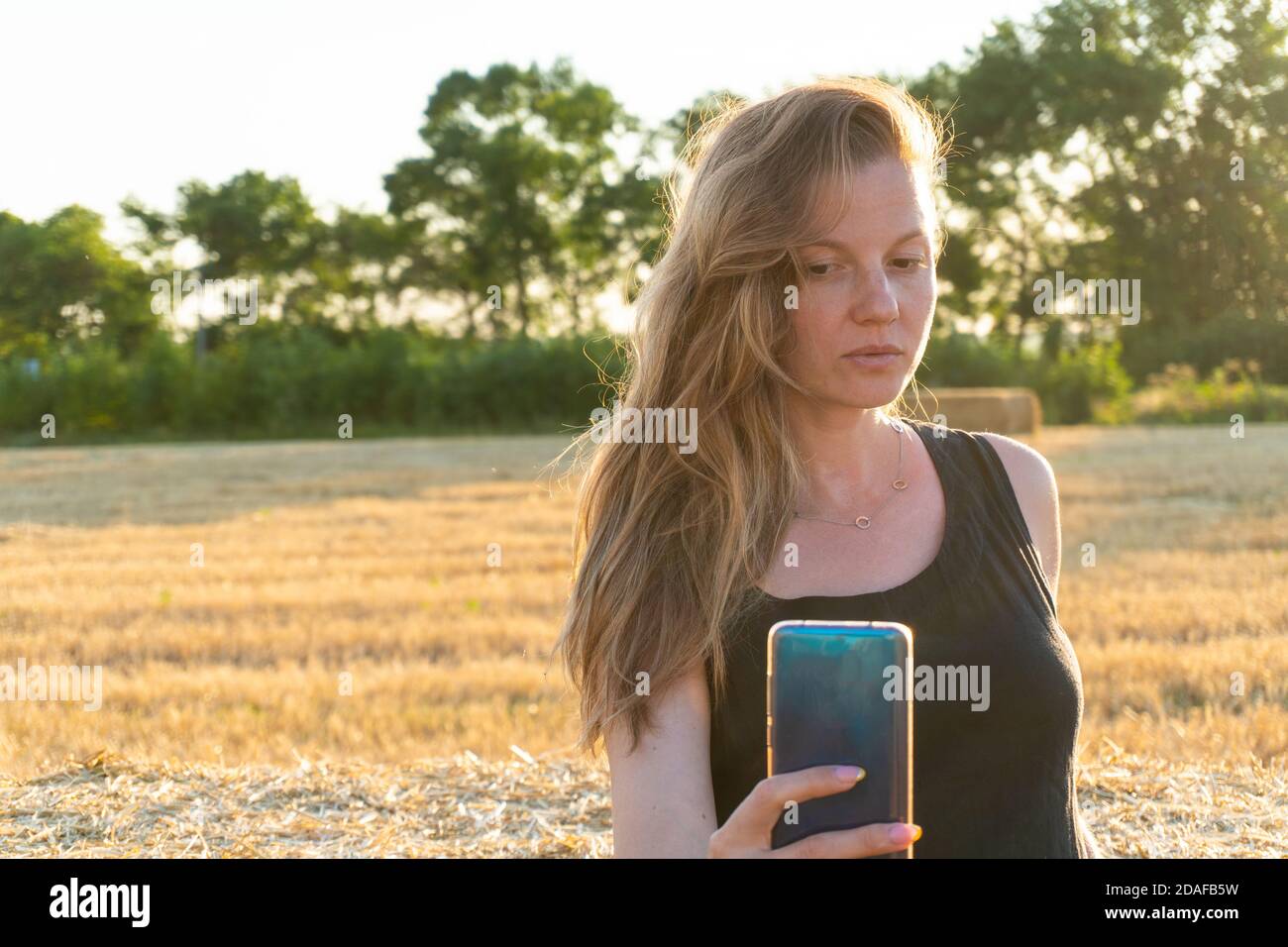 Femme en robe longue noire regardant faire le selfie Banque D'Images