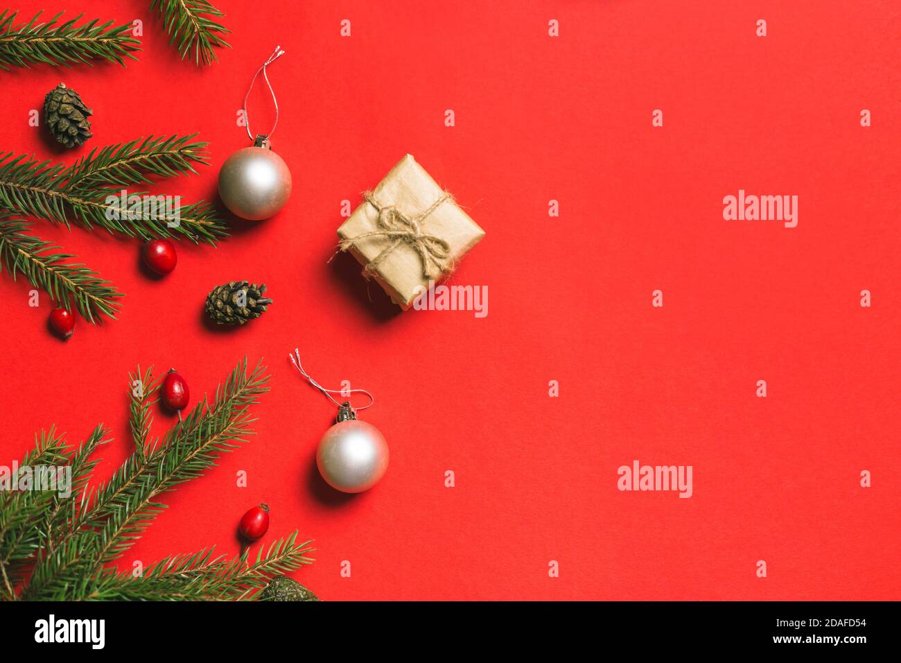 Composition de Noël. Cadre fait de cadeaux de noël, branches de pin, isolé sur fond rouge. Flat lay, vue de dessus Banque D'Images