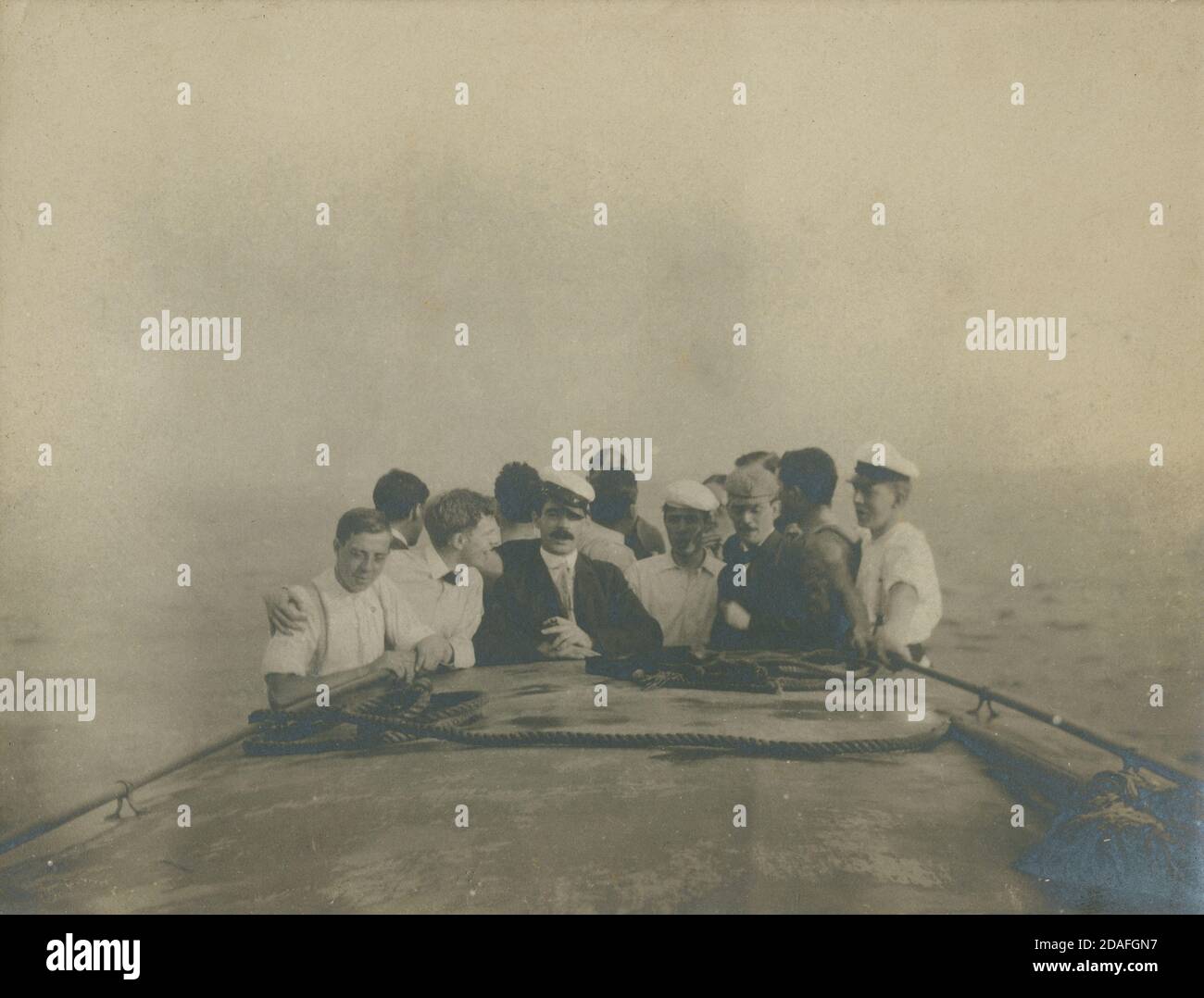 Photographie antique de c1910, groupe d'hommes sur un voilier lors d'une journée de brouillard sur l'océan. Lieu inconnu, peut-être New York, États-Unis. SOURCE : PHOTO ORIGINALE Banque D'Images