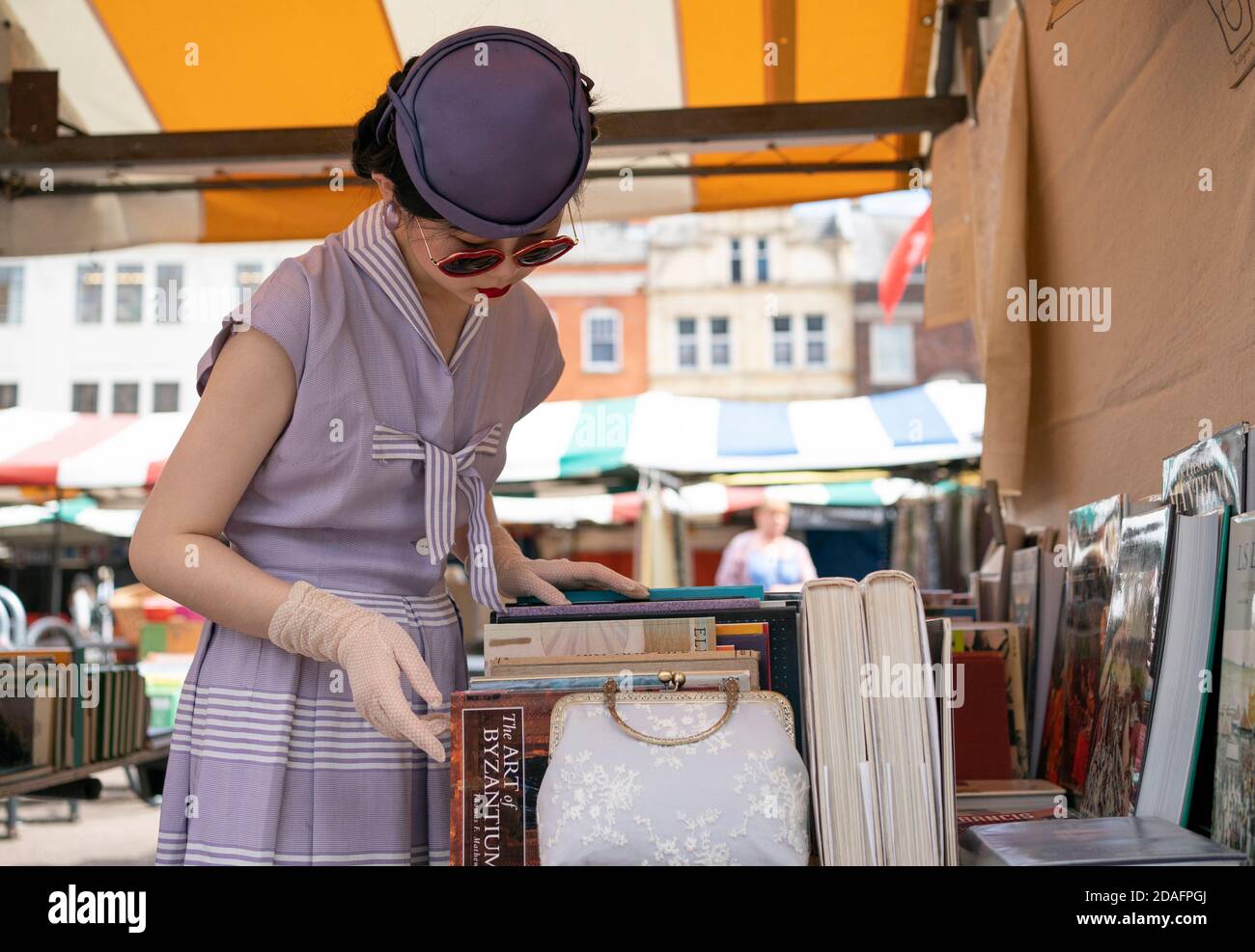 Une femme élégante habillée dans une tenue de style des années 1950, parcourt une cabine de livre à Cambridge Banque D'Images