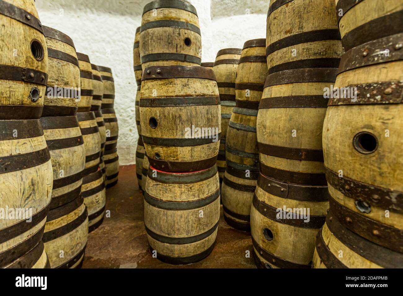 De nombreux tonneaux en bois cerclés de bandes métalliques sont empilés serrées dans la cave taillée dans la roche du Stephansberg à la brasserie Heller-Bräu Schlenkerla de bière fumée à Bamberg, en Bavière, en Allemagne, exploitée par la famille Trum depuis 1866. Les brasseurs étaient autrefois souvent des tonneliers, des charpentiers qui fabriquaient eux-mêmes les tonneaux. Banque D'Images