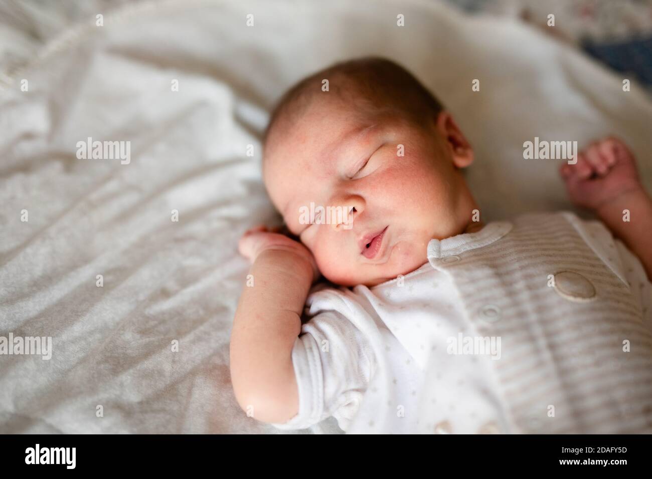 Bébé nouveau-né garçon au lit. Nouveau-né en blanc bodykit couché dans le  berceau de lumière. Les enfants dorment. La literie pour enfants. La sieste  dans le lit. Littl sain Photo Stock 