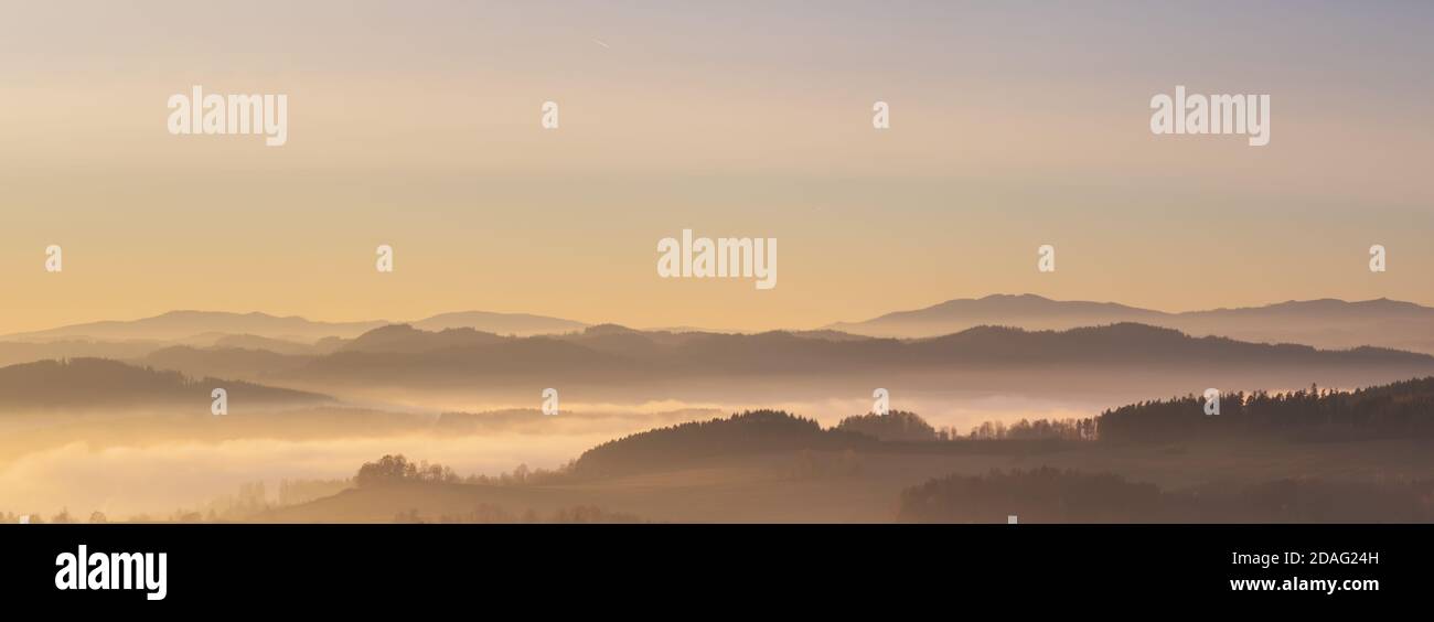 paysage brumeux au coucher du soleil, montagnes qui s'élèvent des nuages de brouillard en arrière-plan, ciel clair Banque D'Images