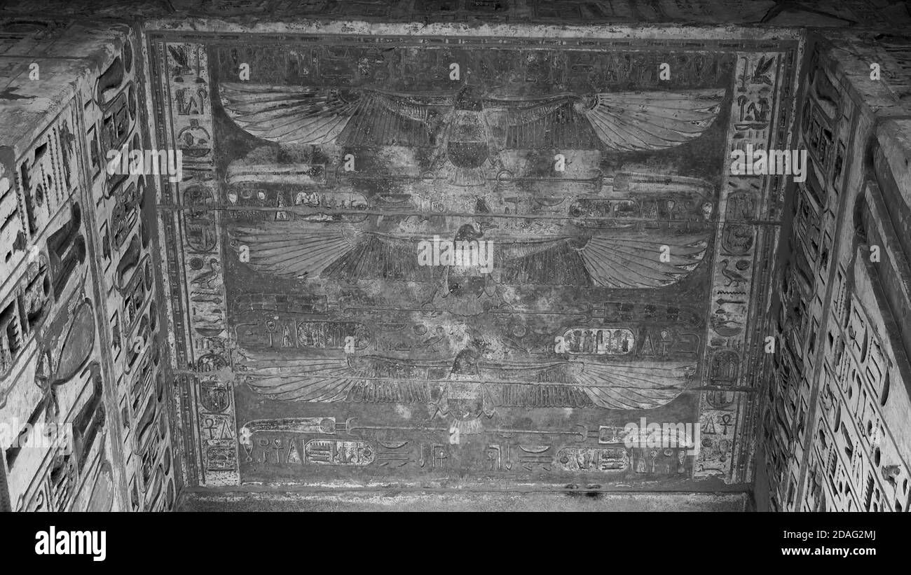 Vieilles sculptures égyptiennes anciennes sur le mur, les gens, les oiseaux, et hiéroglyphes sur le toit d'un temple ancien, beau fond noir et blanc Banque D'Images