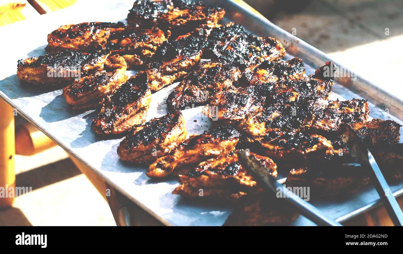 Steak de bœuf trop cuit sur le barbecue, viande grillée brûlée sur une table en acier inoxydable en arrière-plan le jour d'été. Banque D'Images