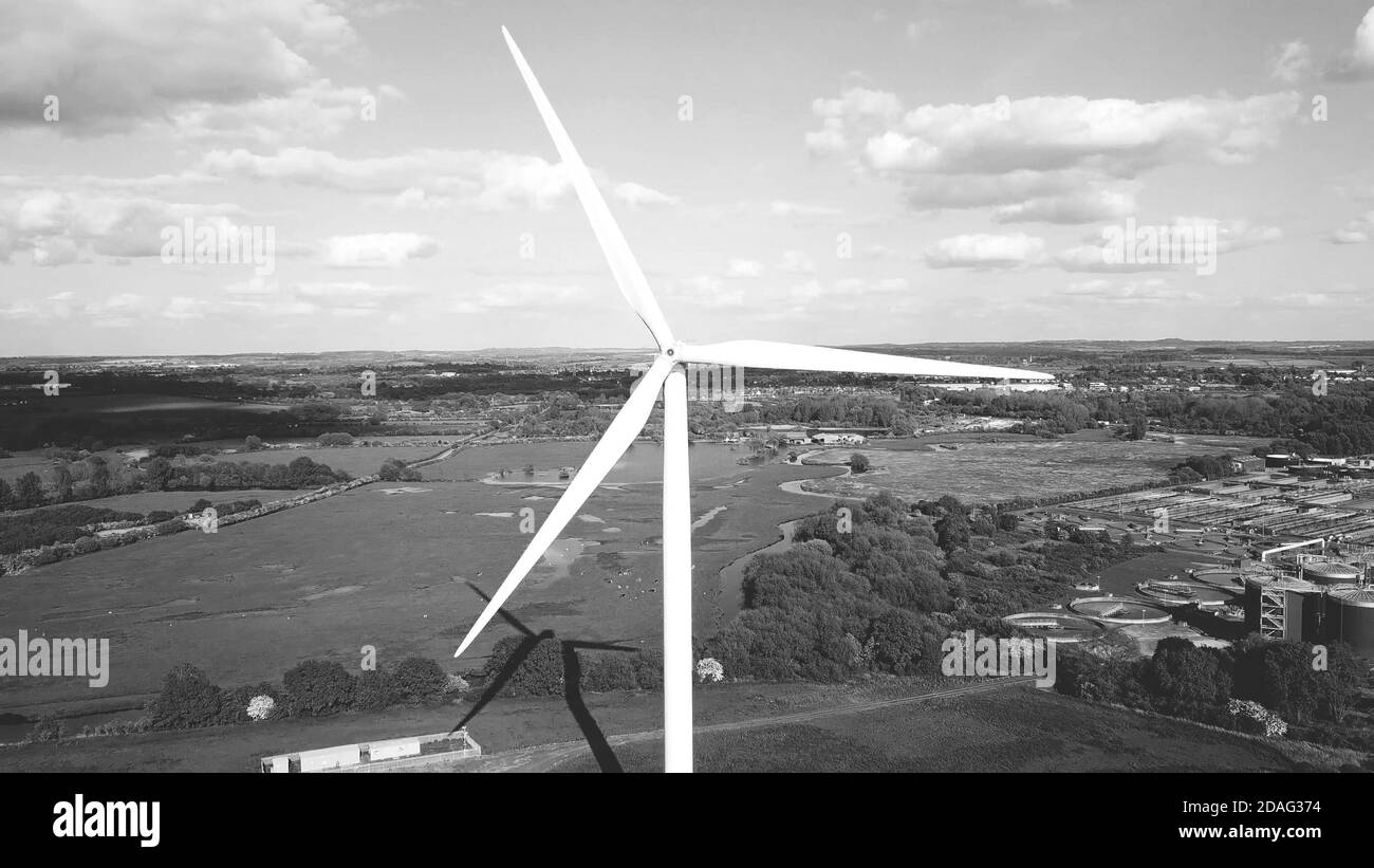 Éolienne, zone industrielle champs agricoles en arrière-plan, production d'énergie propre, vue aérienne en noir et blanc. Banque D'Images