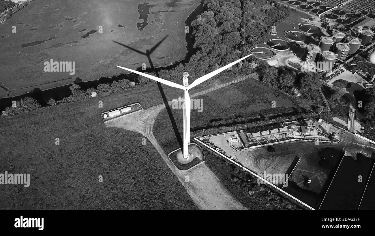 Éolienne contre le quartier industriel, production d'énergie propre, vue aérienne en noir et blanc Banque D'Images