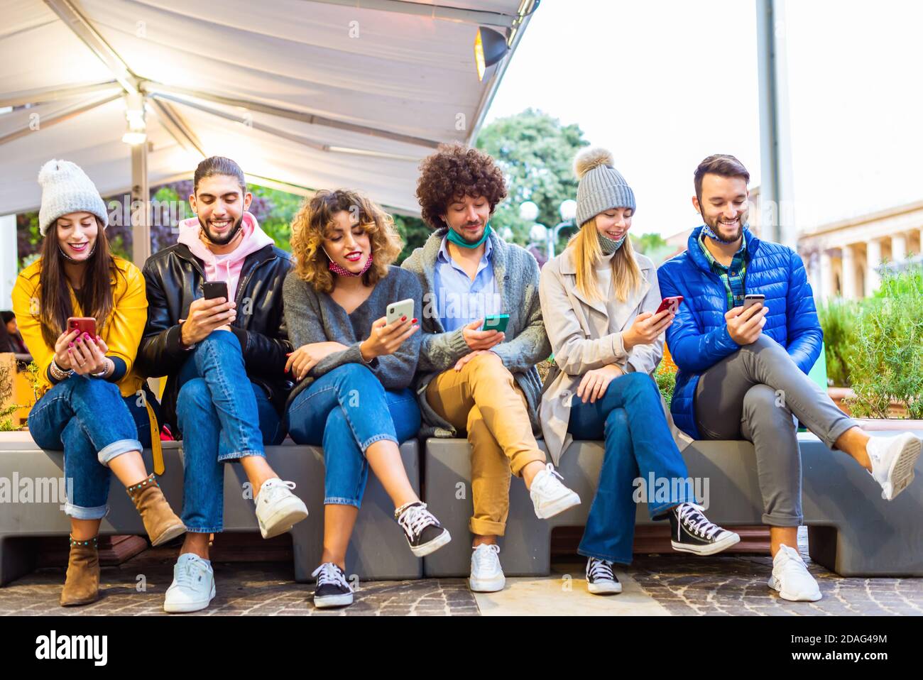 Groupe multiculturel d'amis utilisant l'application de téléphones mobiles intelligents.addiction d'adolescents Aux nouvelles tendances technologiques.les étudiants assis dans une rangée et en tapant Banque D'Images