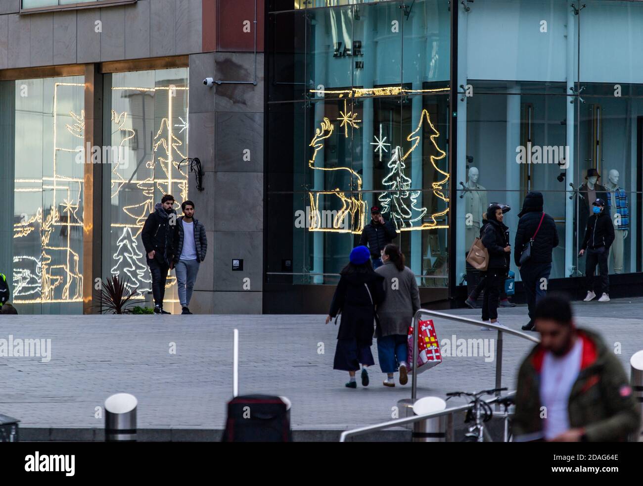 Les amateurs de shopping au Bullring de Birmingham, avec des lumières de Noël réfléchissantes dans les vitrines des magasins Banque D'Images