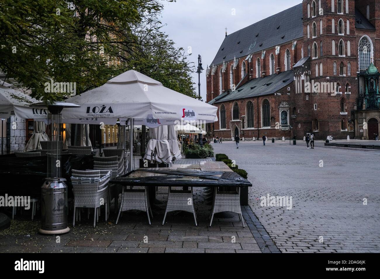 Cracovie, Pologne. 12 novembre 2020. Chaises, tables et parasols provenant d'un restaurant qui se trouve sur la place principale de Cracovie, classée au patrimoine mondial de l'UNESCO, pendant la pandémie de Covid-19.la Pologne traverse maintenant la deuxième vague de coronavirus et introduit de nouvelles mesures restrictives telles que la fermeture de magasins à l'intérieur des centres commerciaux, des rassemblements avec un maximum de 5 personnes, bars et restaurants fonctionnant sur une base de plats à emporter entre autres. La Pologne a enregistré plus de 615,000 infections à COVID-19 et un nombre de décès supérieur à 8000. Crédit : Omar marques/SOPA Images/ZUMA Wire/Alamy Live News Banque D'Images