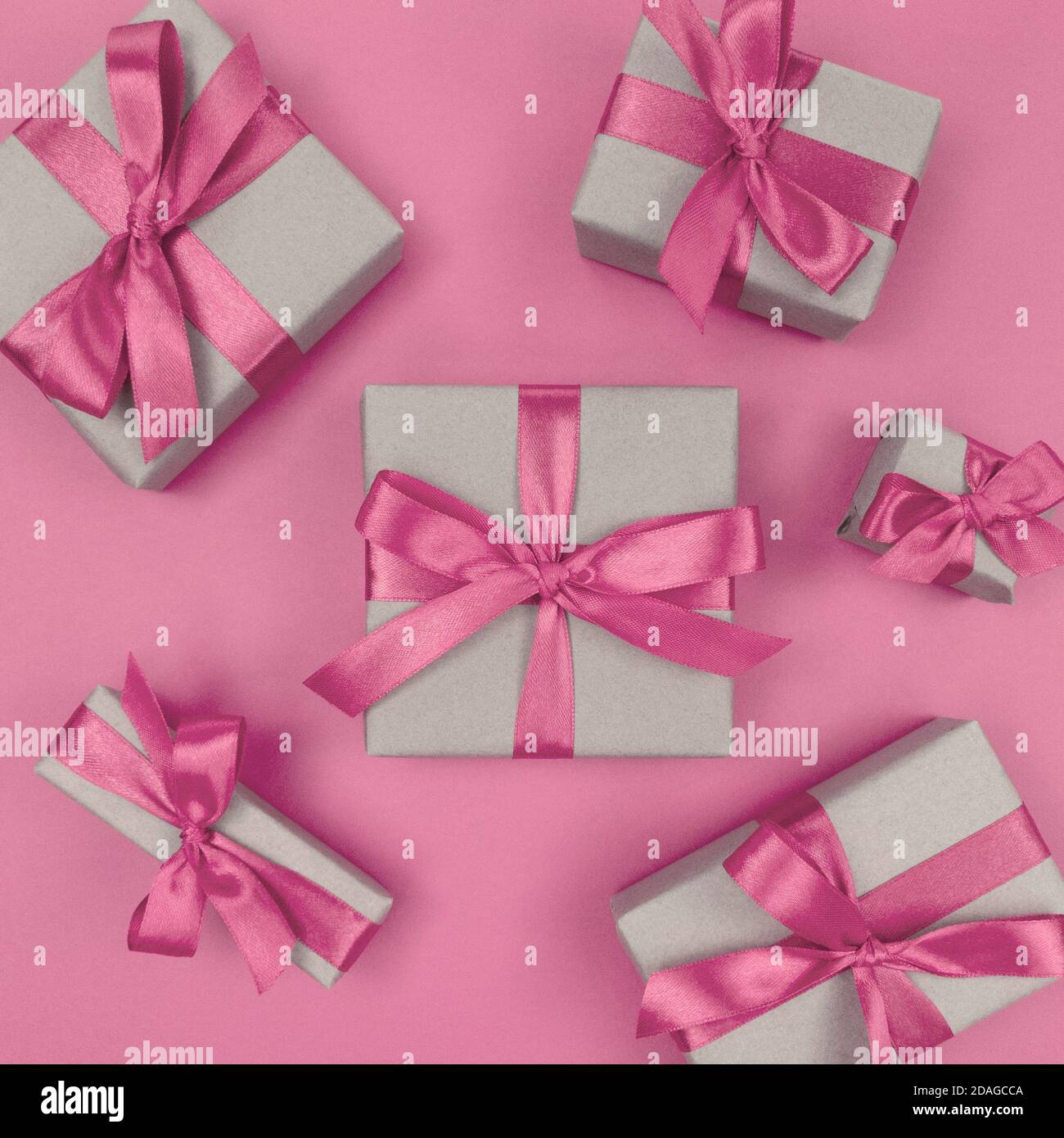 Boîtes-cadeaux emballées dans du papier artisanal avec des rubans et des noeuds roses doux. Flat lay monochrome festif. Banque D'Images