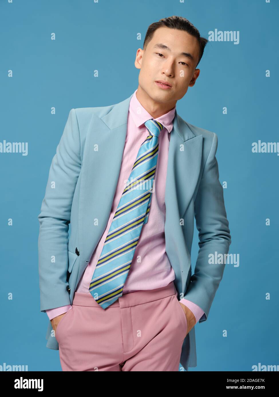 Le joli homme asiatique en costume sur fond bleu se redresse sa veste et  son pantalon rose Photo Stock - Alamy