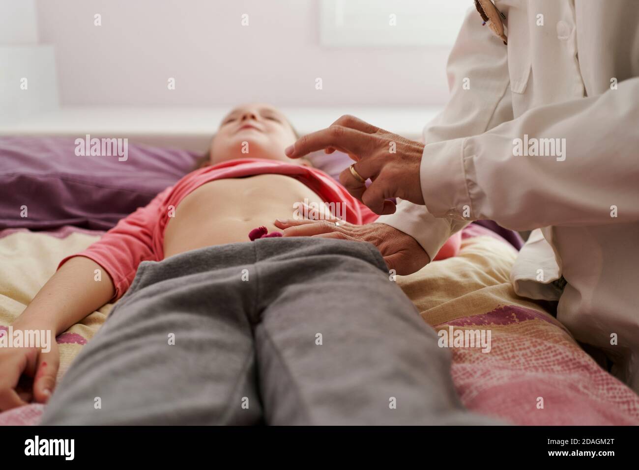 Femme médecin examinant l'abdomen d'une petite fille dans sa chambre. Concept de médecin à domicile Banque D'Images