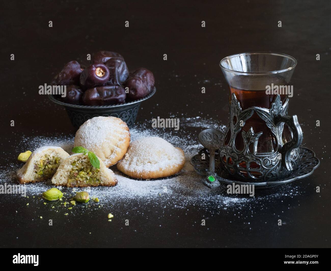 Biscuits égyptiens 'Kahk El Eid' avec dates et tasse de thé servis dans une table noire. Biscuits de la fête islamique El Fitr. Banque D'Images