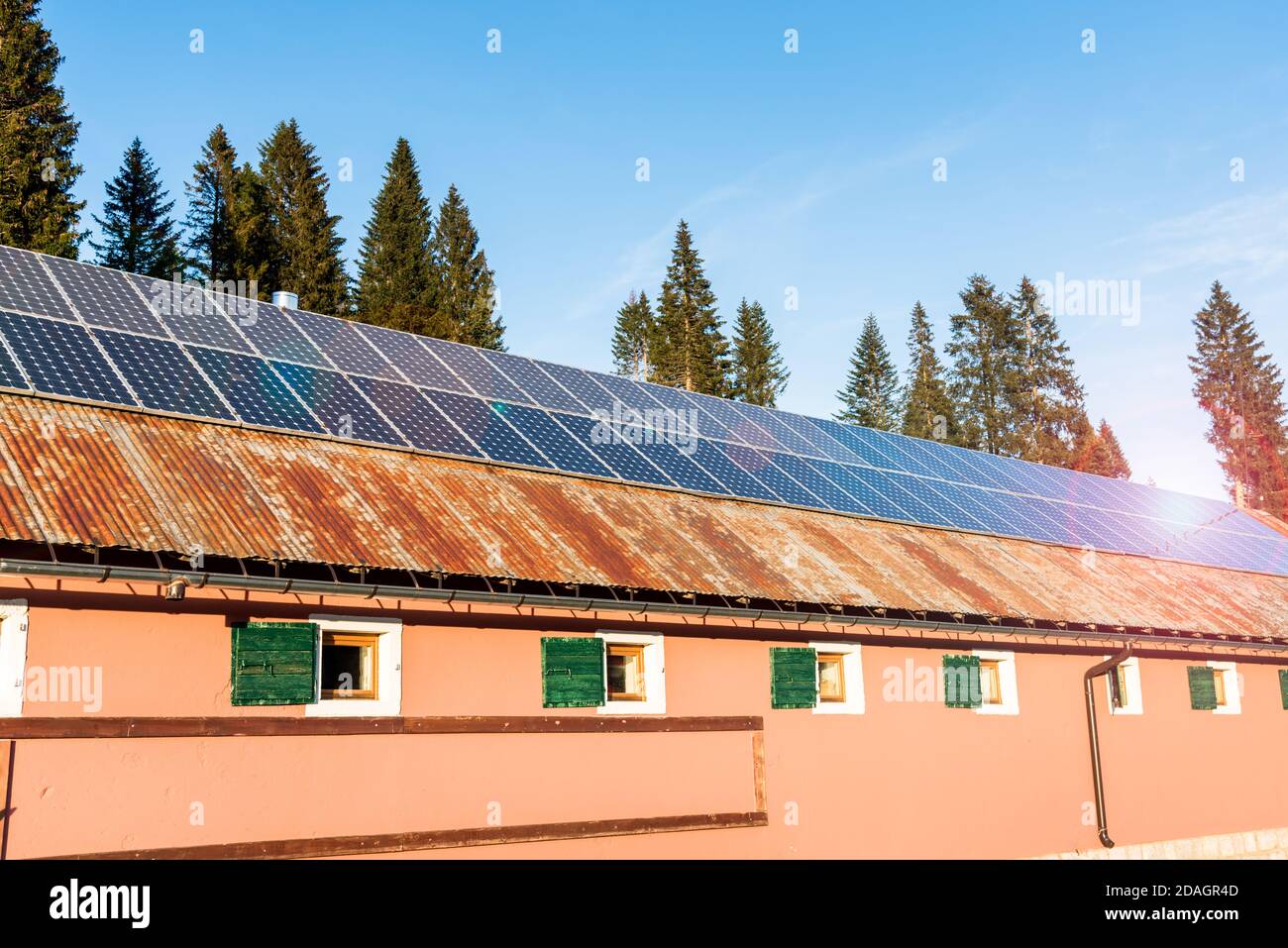 Panneaux solaires pour la production d'électricité sur le toit en étain rouillé d'une grange dans les Alpes européennes lors d'une journée d'automne ensoleillée. Évasement d'objectif. Banque D'Images