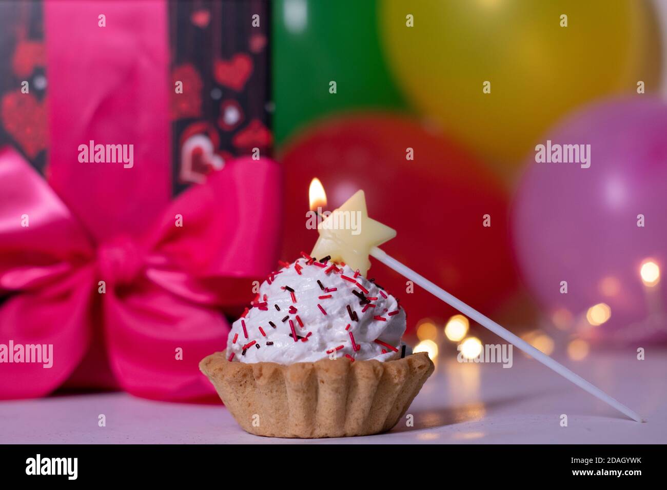 Gateau De Fete Avec Une Bougie Jaune En Forme D Etoile Sur Fond De Boite Cadeau Rouge Avec Ruban Rose Ballons Multicolores Et Lumieres Fete Concept Anniversaire Copier L Espace Photo De Haute