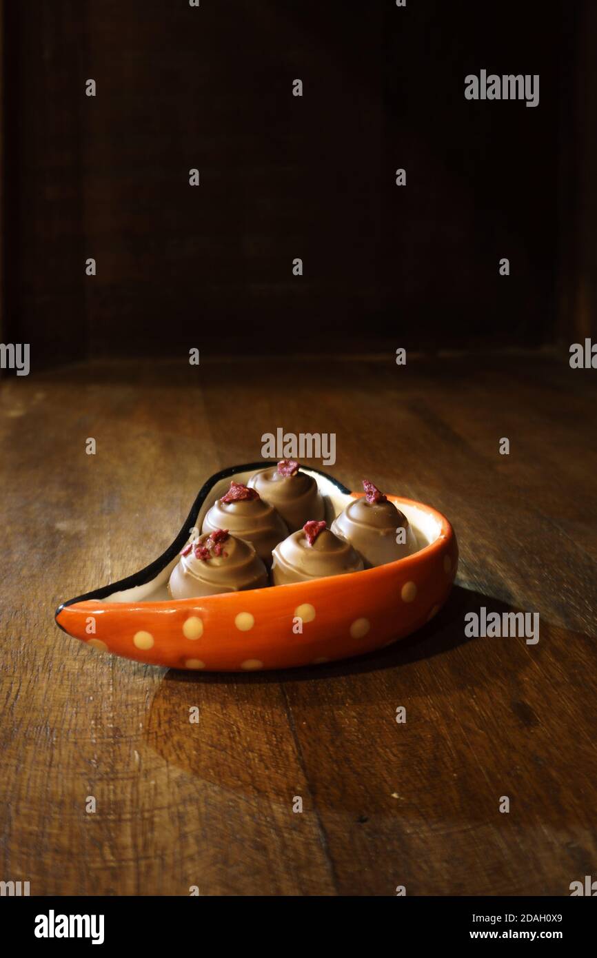 Pralines au chocolat, nappées de framboise, servies en forme de cœur bol sur une étagère en bois Banque D'Images