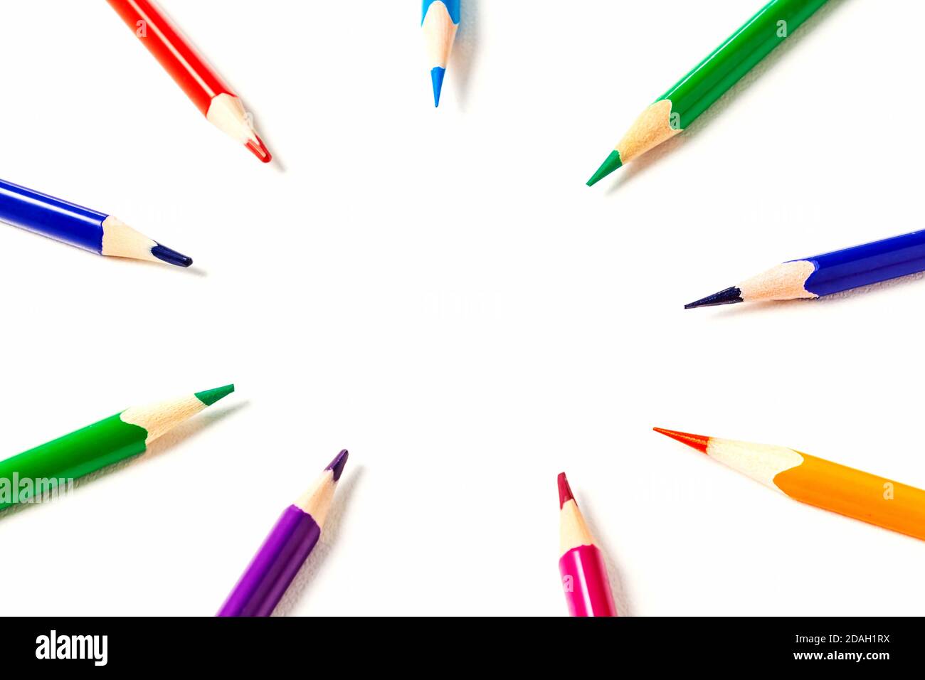Cercle de crayons de couleur aiguisés. L'accent est mis sur l'espace de copie au centre. Les crayons pointent vers votre texte ou votre idée. Vue de dessus. Banque D'Images