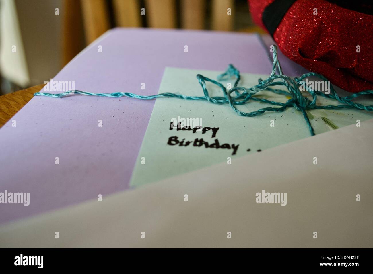 Message manuscrit « Joyeux anniversaire » sur une carte d'anniversaire ou une étiquette sur un cadeau, entouré d'un emballage, de rubans, d'un noeud. Banque D'Images