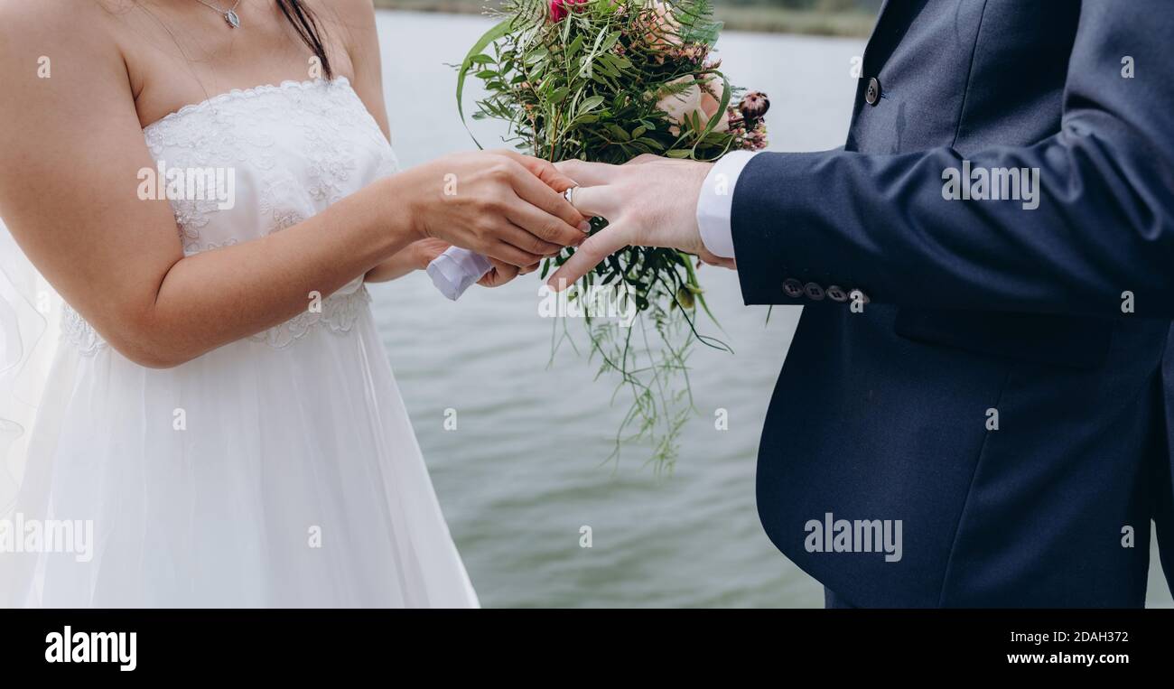 La mariée met un anneau au doigt de marié. Couple de mariage célébrant ensemble le joyeux jour de mariage. Concept d'agence de mariage. Banque D'Images La mariée met un anneau au doigt de marié. Couple de mariage célébrant ensemble le joyeux jour de mariage. Concept d'agence de mariage. Banque D'Images