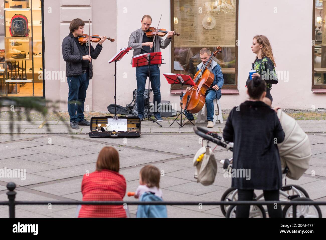 Saint-Pétersbourg, Russie: Une violoniste est à la tête d'une jeune femme qui passe tout en jouant du violon avec un groupe de musique de rue. Banque D'Images